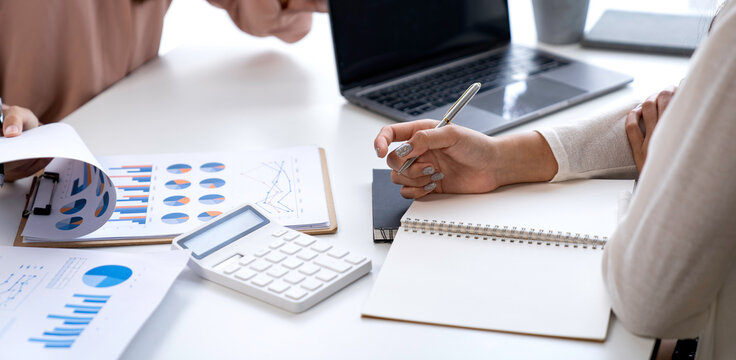 Teamwork process. Two business women calculating a valuation in the workplace. laptop on the table, typing keyboard, analysis of earnings, analyzing graph plans