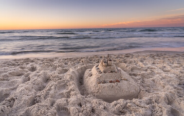 Zamek z piasku, plaża latem. Morze, piasek, niebo podczas złotej godziny.