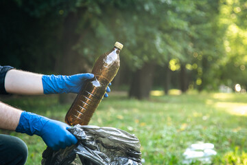 Close-up, a plastic bottle in a male hand, cleaning up nature.