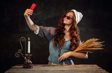 Vintage style. Young charming redhair girl with long curly hair like girl of renaissance eras isolated on dark background. Eras comparison, beauty, art, painting