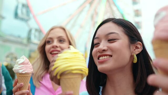 Multiethnic group of friends going out after school and having fun. Teenagers eating a creamy ice cream at the amusement park