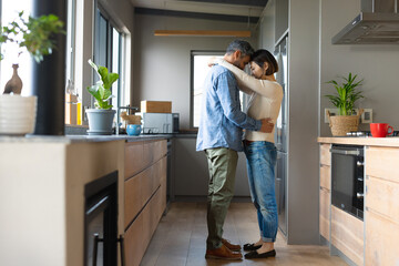 Happy diverse couple dancing together and smiling in kitchen