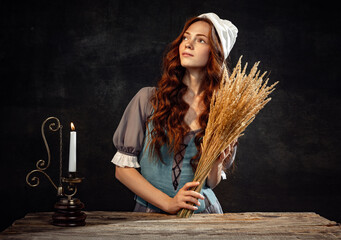 Creative portrait of young beautiful redhead girl with long curly hair in image of medieval person...
