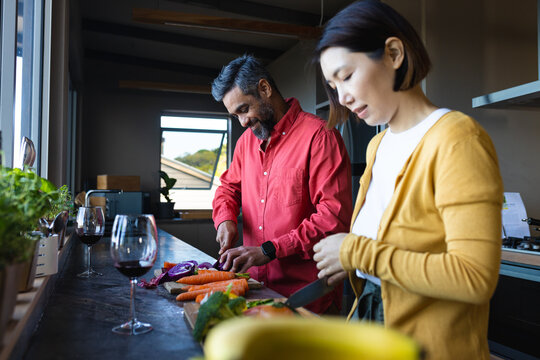 Happy diverse couple preparing dinner together, cooking in kitchen
