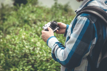 Fototapeta premium Vintage film camera in male hands on a hike in nature.