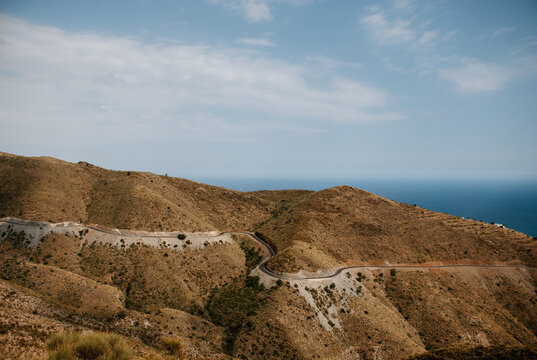 Landscape with the front view of a mountain, the road with curves and the sea in the background. In Adra, Almeria.