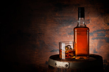 Glass of whiskey with ice cubes and bottle