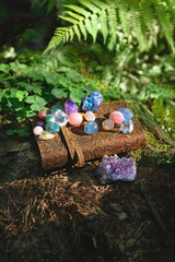 witch spell book and set of minerals on natural forest background. Gemstones for healing Magic...