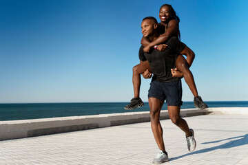 Young multiracial woman piggybacking on male boyfriend outside