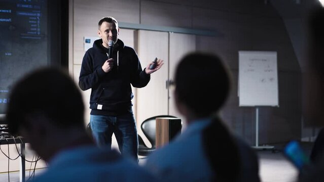 Conference in the IT industry. A young and successful male speaker talks about modern solutions to students and colleagues.