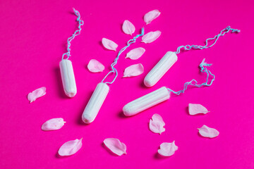 Female tampons with with cherry petals on a pink background. Hygienic white tampon for women. Cotton swab.