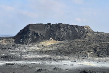 The main vent from the Fagradalsfjall 2021 eruption, Iceland, taken one year later. Mineral deposits can be seen on the lava field in front. Volcanic crater with lava field in the foreground. © Creative by Nature