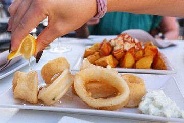 squid kalmar rings, lemon juice and potato with garlic sauce aioli and tomato ketchup on square plate with human hands close up photo © ulianna19970