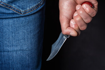 Man holding a knife in a threatening stance ready to fight - obrazy, fototapety, plakaty