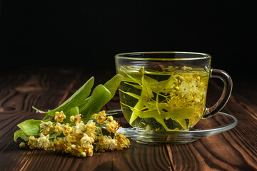 Cup of herbal tea with linden flowers on a wooden background