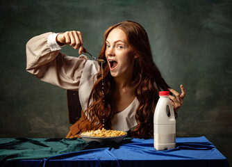 Portrait of charming redhair girl with long curly hair like girl of renaissance eras eating...