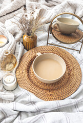 Cozy autumn composition with a cup of coffee and candles in bed.
