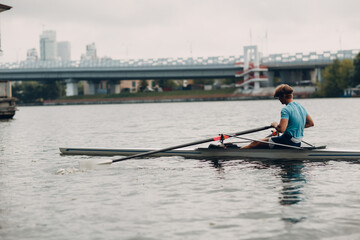 Sportsman single scull man rower rowing on boat. © primipil
