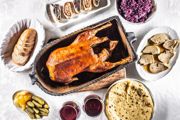 Roast goose with side dishes, red cabbage, roast, strudel, potato dumplings, pickles, bread and red wine. Traditional holiday food. Top view. © weyo