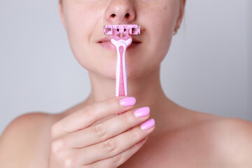 Face hair depilation. woman shaving upper lip with razor. Beautiful young female making domestic...