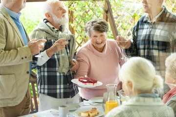 Cheerful group of elderly friends during barbeque at garden of family home