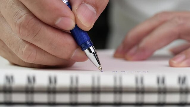 Close up hand writing paper on notebook with blue pen to note, memo, list action plan at office or home desk, selective focus 4k resolution. Concept of writing paper, letter, pen, notepad, diary