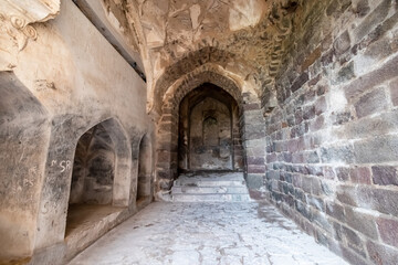 Obraz premium Stone walls and arches in a corridor inside the ruins of the ancient historic Golconda Fort in Hyderabad.