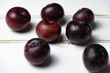 Red plums on a white wooden background, red plum concept idea photos