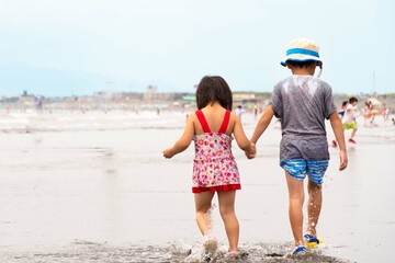 海水浴場の砂浜を歩く仲良し兄弟