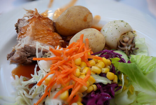Auf einem Teller liegt ein St&uuml;ck Schweinebraten zusammen mit Salat.