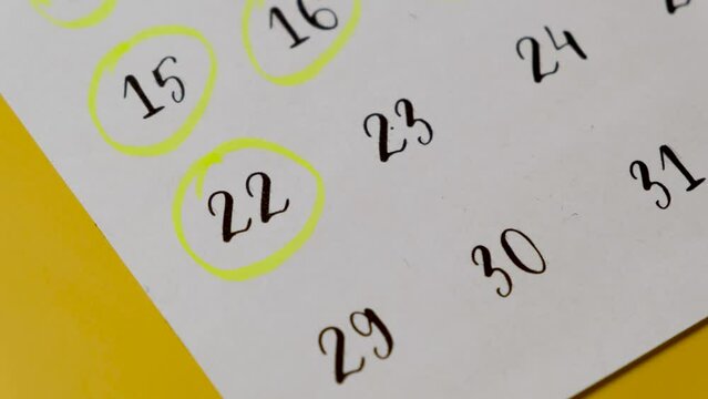 The hand circles the date in the calendar with a marker. 22th of the month.
