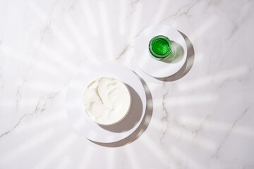 A mock-up of a round cosmetics container with cream on marble background, top view