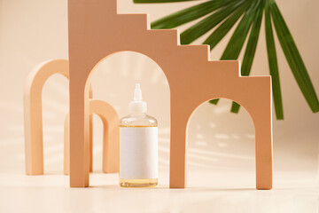 A mock-up of a transparent cosmetics bottle with yellow liquid and white label in peach colored...