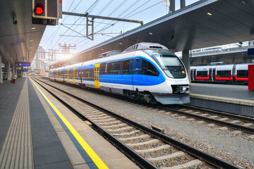 High speed train on the train station at sunset in Vienna, Austria. Beautiful blue modern intercity passenger train on the railway platform. Railroad in Europe. Commercial transportation. Railway - obrazy, fototapety, plakaty