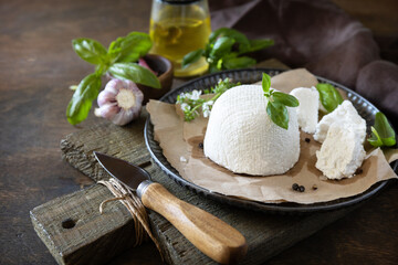 Homemade Italian ricotta cheese or cottage cheese with basil on a rustic table. Vegetarian healthy...