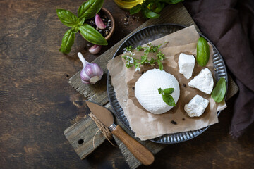 Homemade Italian ricotta cheese or cottage cheese with basil on a rustic table. Vegetarian healthy...