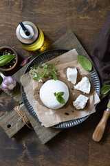 Homemade Italian ricotta cheese or cottage cheese with basil on a rustic table. Vegetarian healthy diet, fermentation food concept. View from above.