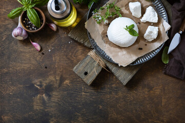 Homemade Italian ricotta cheese or cottage cheese with basil on a rustic table. Vegetarian healthy...