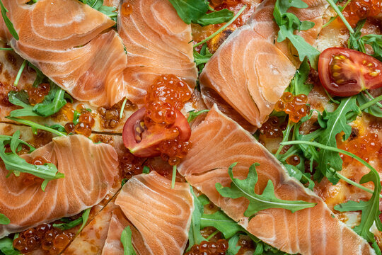 Delicious hot pizza with salmon, red caviar, tomatoes and aragula ready to eat. banner, menu, recipe top view