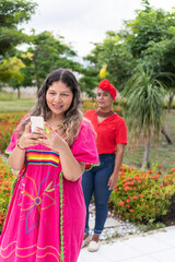 Latin woman using a cell phone and waiting for her friend