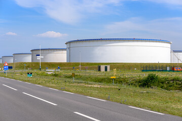 Fototapeta na wymiar Large crude oil storage tanks in a oil terminal on a sunny summer day