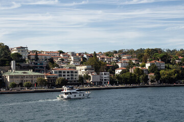 Fototapeta premium View of a yacht passing on Bosphorus and Baltalimani neighborhood on European side of Istanbul. It is a sunny summer day. Beautiful travel scene.