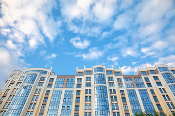 Fototapeta premium multi-storey residential building on the background of the sky with clouds. Modern high-rise residential building.