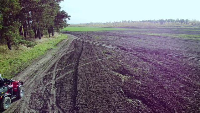 Off-road quad biking along the forest and field, shooting with a drone