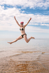 Happy funny woman jumping in the water of sea