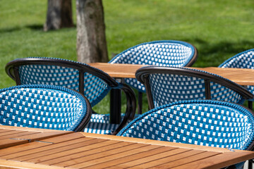 Outdoor cafe - restaurant tables and chairs, with no customers in a garden atmosphere in bright...