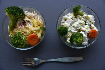 Salads with mayonnaise and vegetables with meat in glass salad bowls on a black background. Delicious salads with forks on a black background. Salads with a still life.