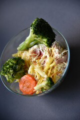 Salads with mayonnaise and vegetables with meat in glass salad bowls on a black background. Delicious salads with forks on a black background. Salads with a still life.