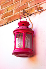 a red little lantern hangs on a white brick wall
