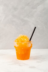 Refreshing Slushie drink in disposable plastic cup. Orange Granizado. Summer ice drink. Sweet...